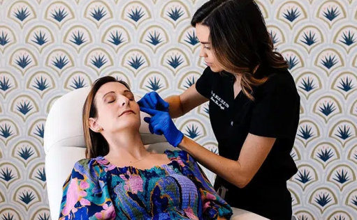 A woman receiving a facial treatment from a beautician