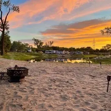 Sandy beach with a fire pit and RVs at sunset
