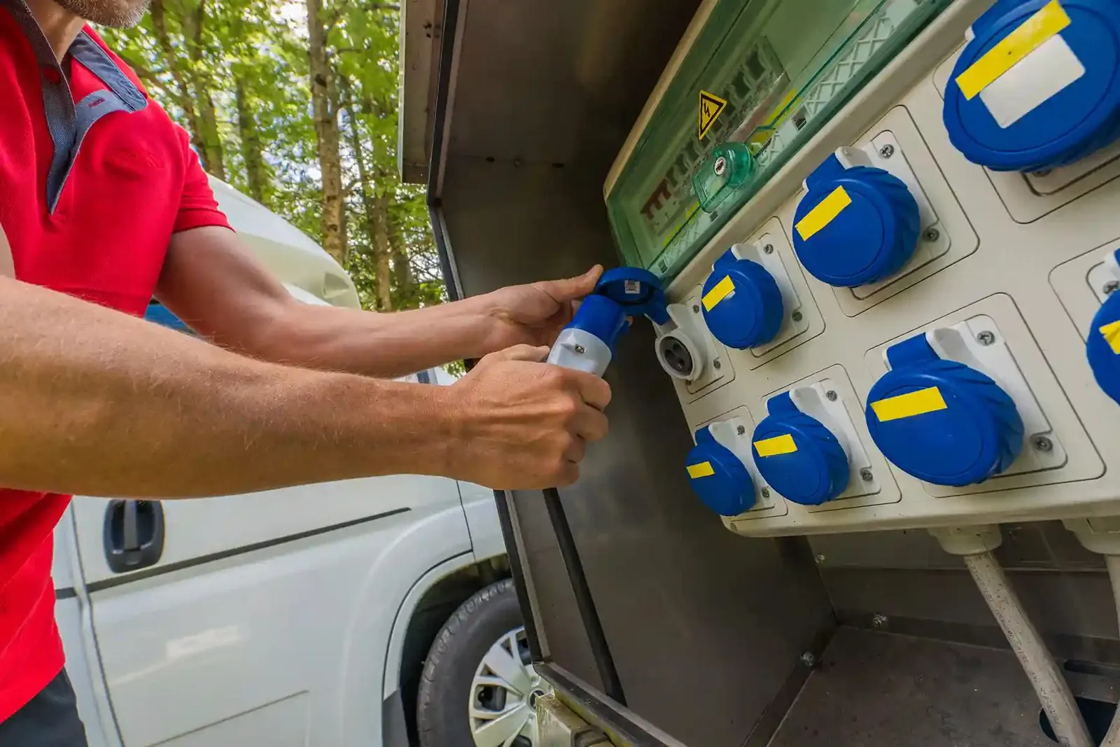 Hand connecting an RV to a power pedestal