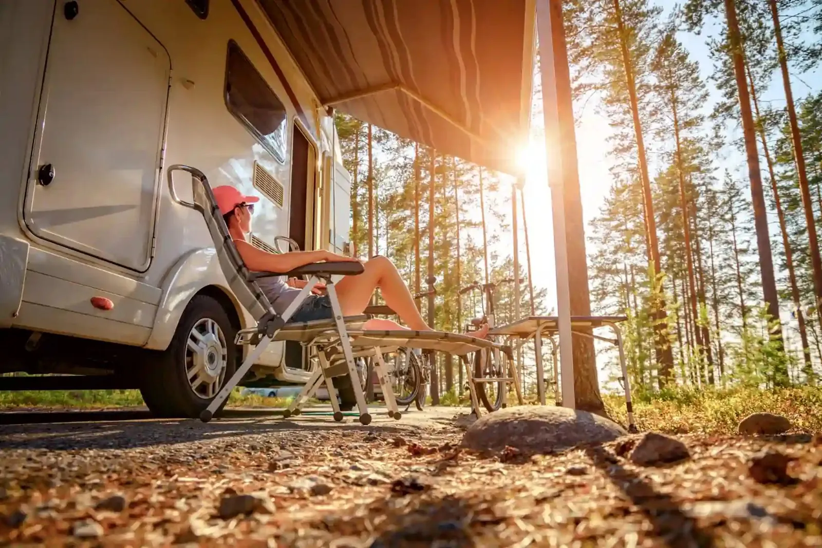 Camper relaxing in a chair beside an RV in the woods